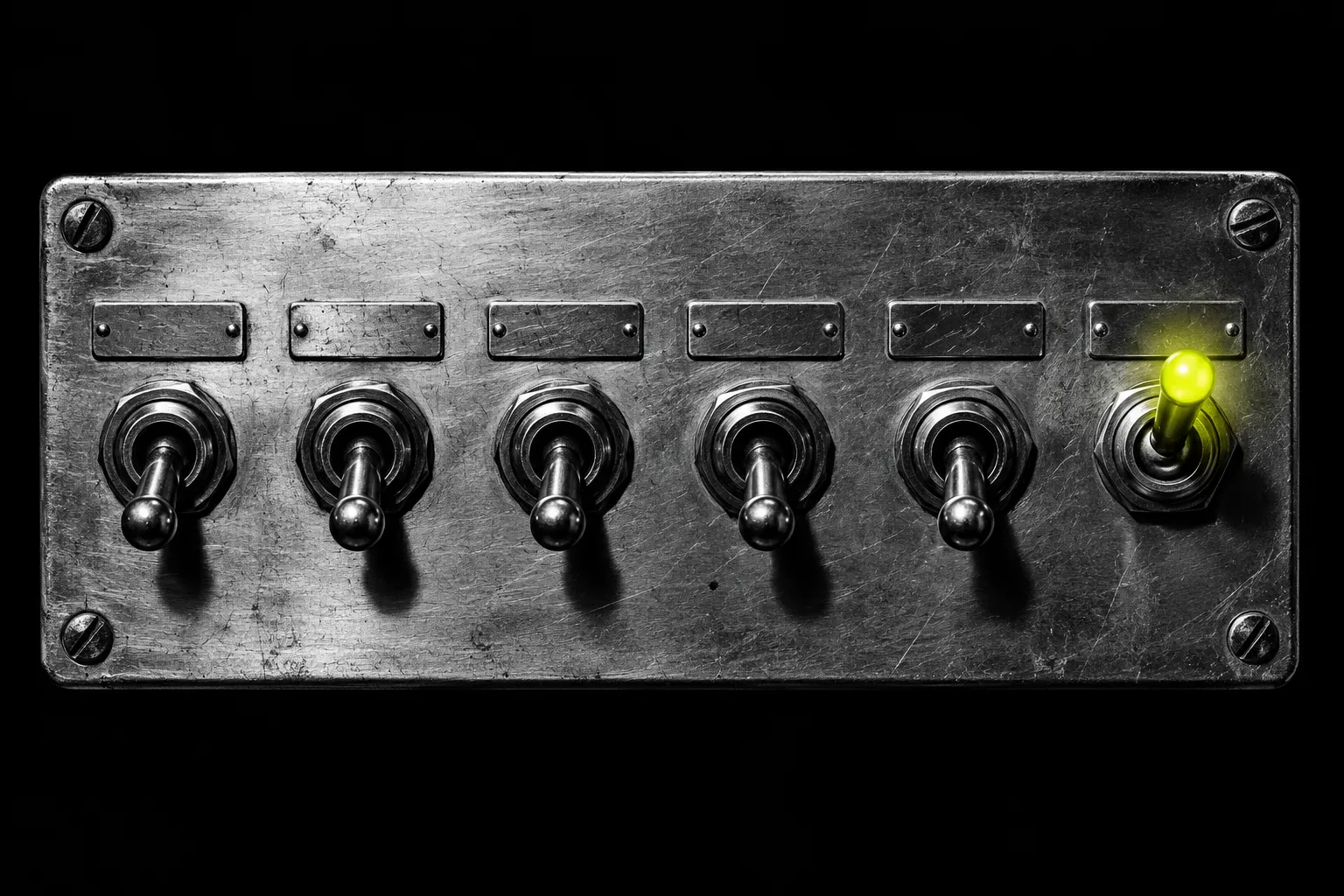 A row of metal toggle switches on black; the last one is flicked up and glows yellow-green.